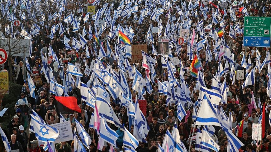 People rally waving Israeli flags against the government's judicial reform bill near parliament in Jerusalem on February 20