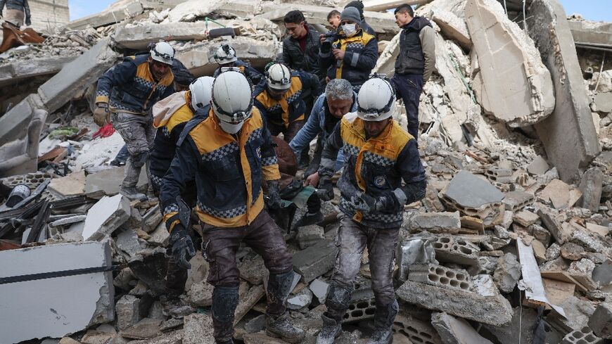 White Helmets rescuers emerge from the rubble with a casualty from the earthquake in the village of Azmarin, in Syria's rebel-held northwestern Idlib province