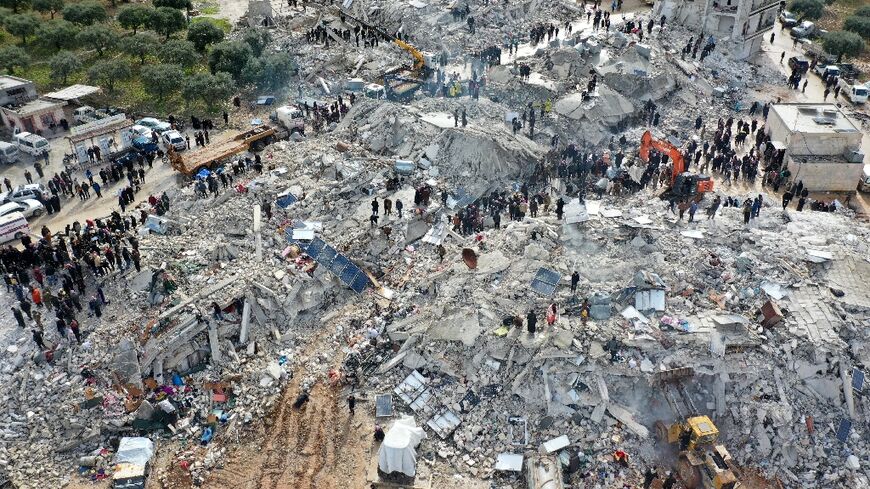 An aerial view of residents searching for survivors in the Syrian village of Besnia in rebel-held Idlib province