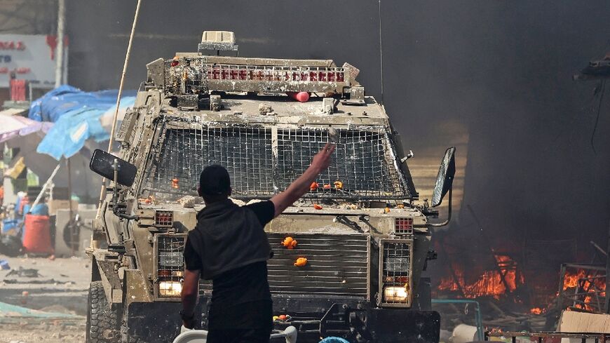 A Palestinian faces an Israeli military vehicle during a raid on the occupied West Bank city of Nablus