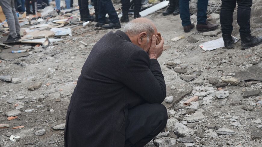 A man puts his head in his hands as people search for survivors in Diyarbakir, southeast Turkey