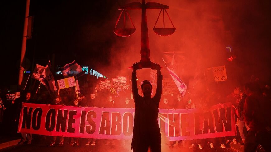 Israeli protesters lift a banner during a rally in central Tel Aviv on February 11 against controversial legal reforms being touted by the country's hard-right government