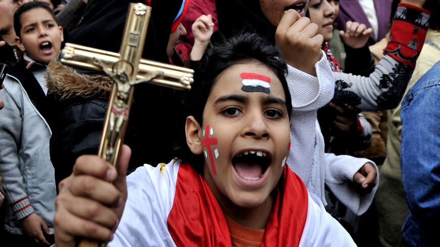 An Egyptian Coptic Christian boy shouts slogans while holding a crucifix during a protest outside the Egyptian state TV building following sectarian clashes, Cairo, Egypt, March 10, 2011.