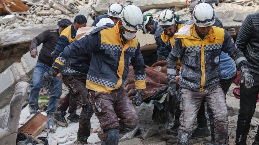 Members of the Syrian Civil Defense, or White Helmets, carry a quake victim from the rubble