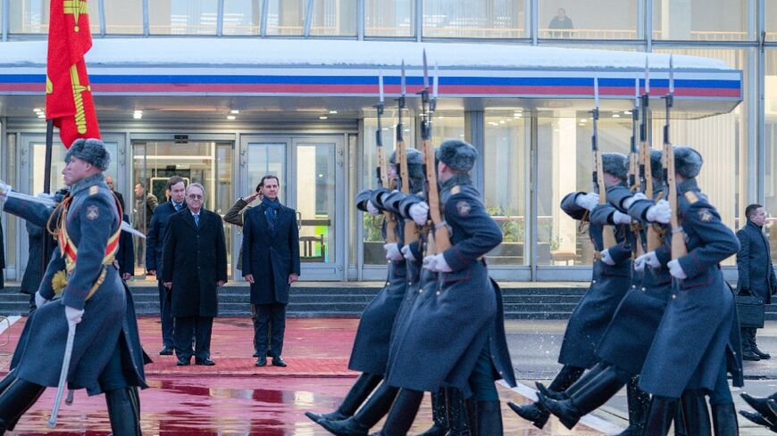 Syria's President Bashar al-Assad (background R) being received upon arrival in Moscow 