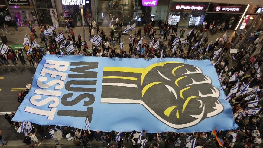 Israelis in Tel Aviv carry a sign during their latest weekly protest against the government's judicial reforms