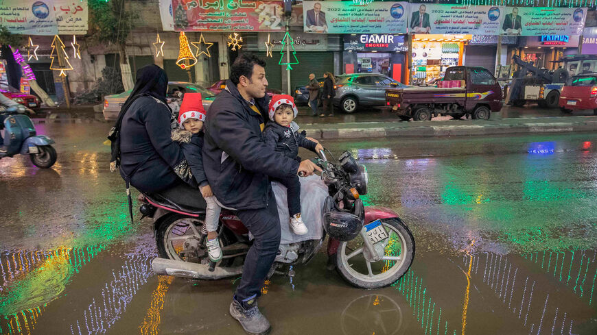 A man rides a scooter with a woman and two children along a main street adorned with Christmas and New Year's decorations, in the northern suburb of Shubra (home to a large Christian population), Cairo, Egypt, Dec. 31, 2021.