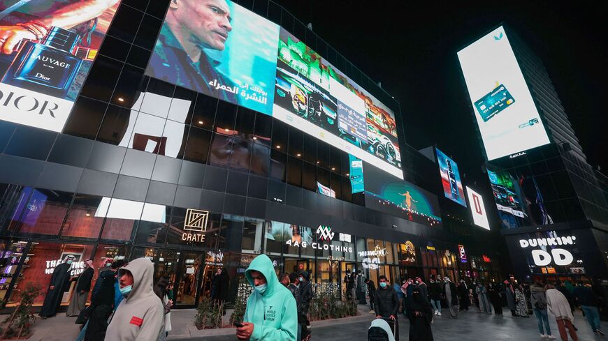 People walk beneath advertisement billboards at Boulevard entertainment city in the Saudi capital Riyadh, late on January 19, 2022.  (Photo by FAYEZ NURELDINE/AFP via Getty Images)