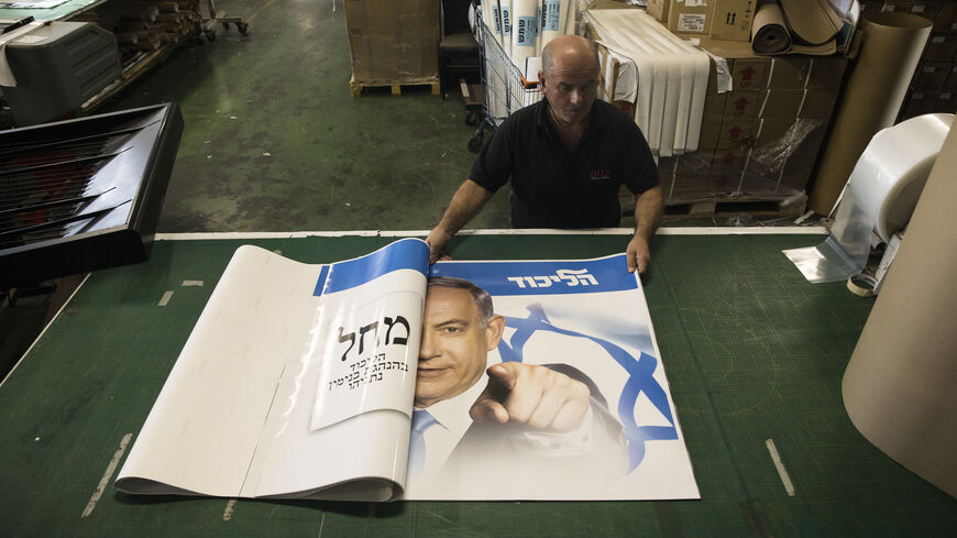 A print house worker rolls up a Likud party election campaign poster that shows former Israeli Prime Minister and Likud Party leader Benjamin Netanyahu on October 19, 2022 in Rosh HaAyin, Israel. Legislative elections will be held in Israel on 1 November 2022 to elect the members of the twenty-fifth Knesset. (Photo by Amir Levy/Getty Images)