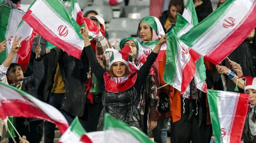 Women football fans wave Iranian flags during the friendly match between Iran and Russia at Azadi Stadium in Tehran