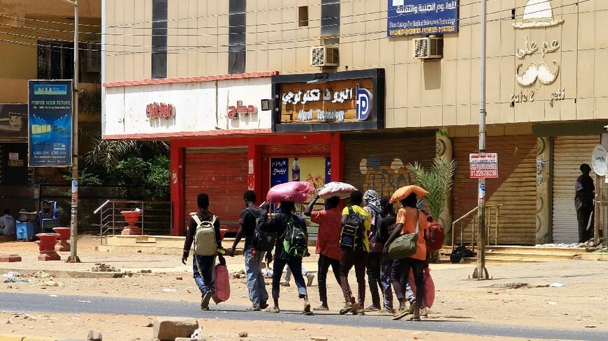 People carry their belongings in Khartoum on Sunday as fighting continues between rival forces