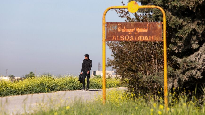 A man walks past the sign of Al-Suwaydah village near Jarablus in Syria's Aleppo province after the US helicopter raid