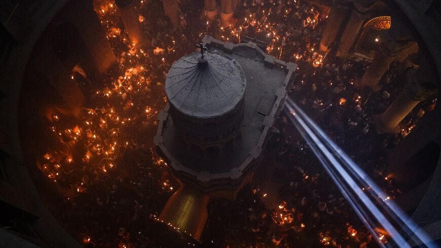 A beam of light enters the Church of the Holy Sepulchre as Christians crowd with candles around the Edicule, traditionally believed to be the burial site of Jesus