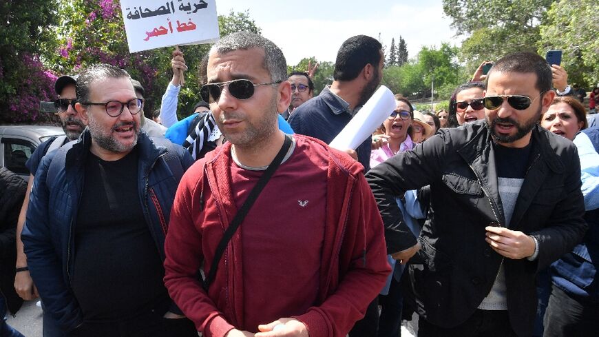 Haythem El Mekki (C) and Elyes Gharbi (L) surrounded by protesters in Tunis 