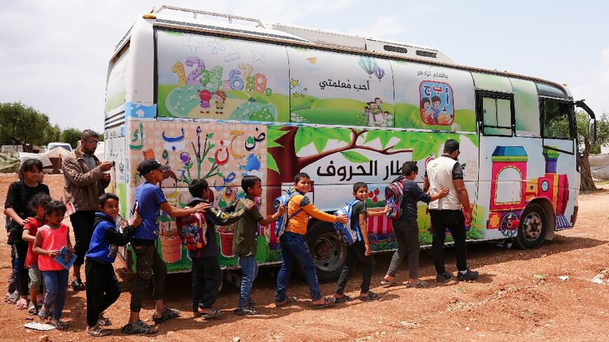 Pupils board a bus turned into a travelling classroom in northwest Syria