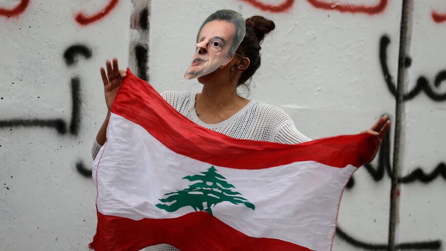 A Lebanese anti-government protester hold a mask of Lebanon's Central Bank Governor Riad Salameh during a protest in front of the central bank headquarters in Beirut to protest against the economic policies of the bank on November 27, 2019. - Since September, debt-saddled Lebanon has had a liquidity crisis, with banks rationing the supply of dollars. As a result, the dollar exchange rate on the parallel market has topped 2,000 Lebanese pounds -- a spike from the pegged rate of 1,507. (Photo by JOSEPH EID /