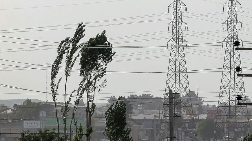 Tree branches flutter near high voltage transmission towers (electricity pylons) during a sandstorm in the south of the capital Tehran on July 4, 2022. (Photo by ATTA KENARE / AFP) (Photo by ATTA KENARE/AFP via Getty Images)