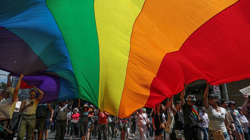 Protesters hold a giant rainbow flag as they march along Oxford St ahead of the pontifical requiem Mass for Cardinal George Pell on February 02, 2023 in Sydney, Australia. Cardinal George Pell, a former senior Catholic Church official who was accused of sexual violence in Australia and then cleared, died on 10 January 2023 aged 81 years old. His body was returned to Sydney after his funeral at the Vatican and will lie in state at St. Mary's Cathedral on Feb. 1 and 2. (Photo by Roni Bintang/Getty Images)