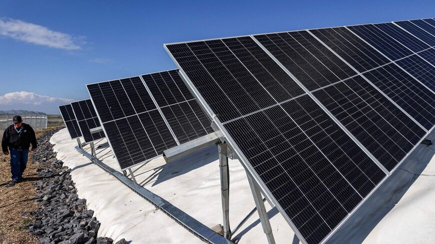 An Israeli worker walks between solar panel rows laid out at a farm on the outskirts of Moshav Haspin in the Israel-annexed Golan Heights near the border with Syria on January 8, 2023. (Photo by JALAA MAREY / AFP) (Photo by JALAA MAREY/AFP via Getty Images)