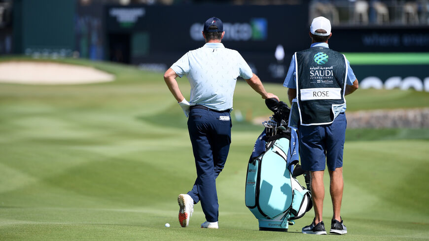 Justin Rose of England and his caddy look on.