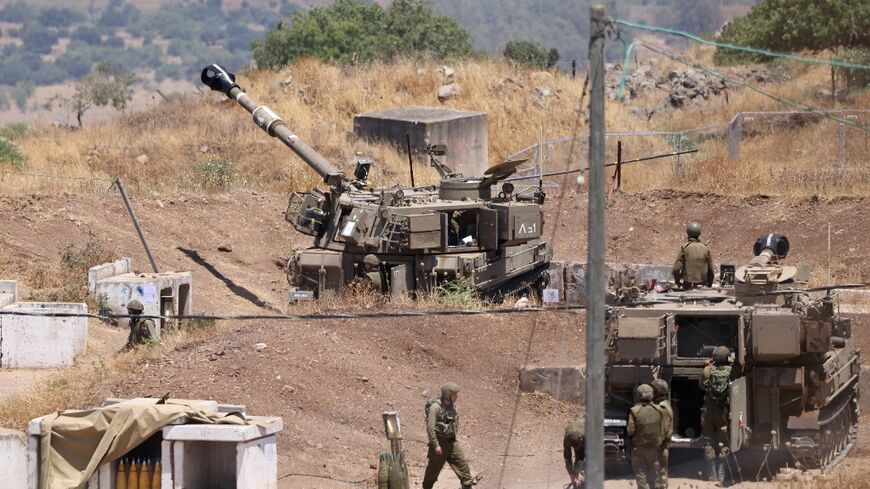 Israeli soldiers stand near army self-propelled artillery vehicles on the outskirts of Kiryat Shmona near Israel's border with Lebanon on July 6, 2023