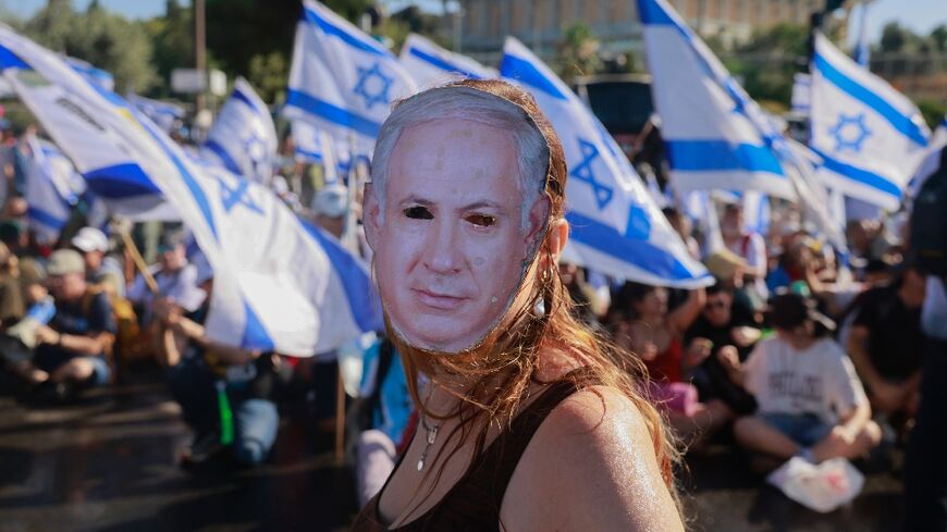 A demonstrator wearing a mask depicting Israeli Prime Minister Benjamin Netanyahu takes part in a sit-in at the entrance to Israel's parliament, just before a vote on the judicial overhaul plans