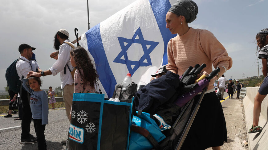 Israeli settlers march toward the outpost of Eviatar, near the Palestinian village of Beita, south of Nablus, West Bank, April 10, 2023.