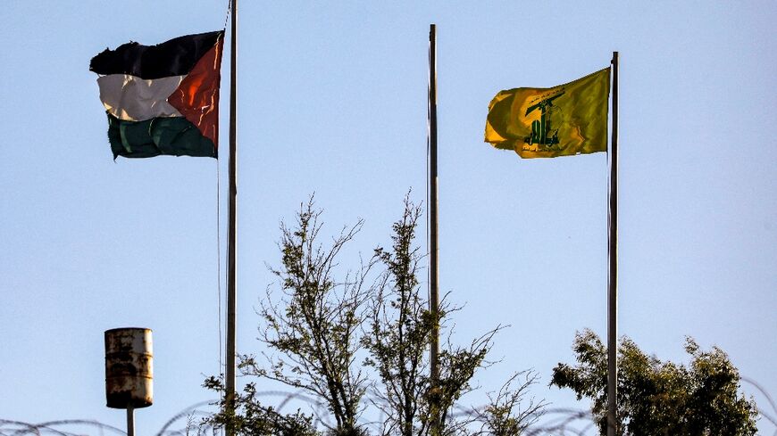 A Palestinian flag and the yellow banner of Hezbollah fly on the Lebanese side of the border with Israel