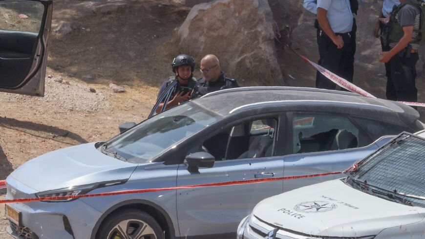 Members of Israeli security forces and emergency services stand at the site of a reported attack south of Hebron in the occupied West Bank