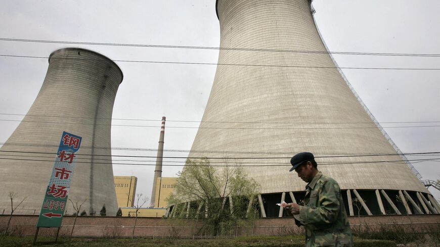 A man walks past a power station on the outskirts of Beijing, April 7, 2005.