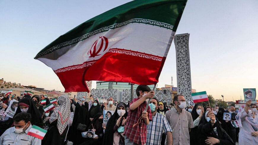 A boy waves an Iranian national flag as supporters of Iran's newly-elected president Ebrahim Raisi celebrate his victory in Imam Hussein square in the capital Tehran on June 19, 2021.