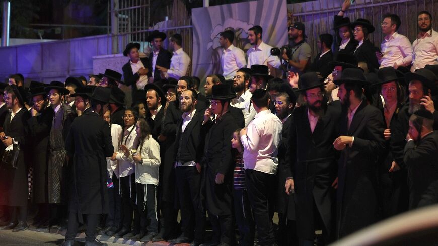 Ultra-Orthodox Jewish bystanders watch emergency and security personnel at the scene of the attack