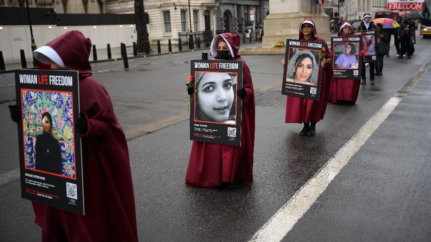 Demonstrators hold placards reading "Women, Life, Freedom" in support of Iranian women at a rally in central London on March 8, 2023