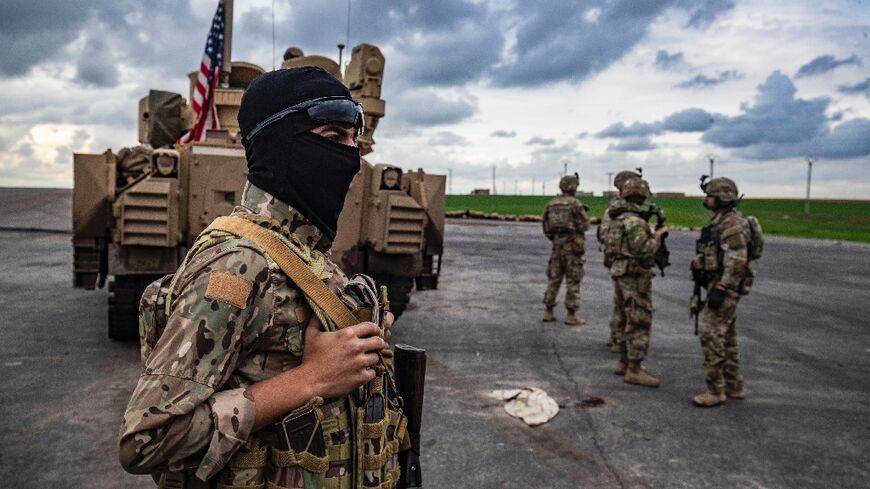 A member of the Syrian Democratic Forces and US soldiers are pictured on the outskirts of Rumaylan in Syria's northeastern Hasakeh province, bordering Turkey, on March 27, 2023