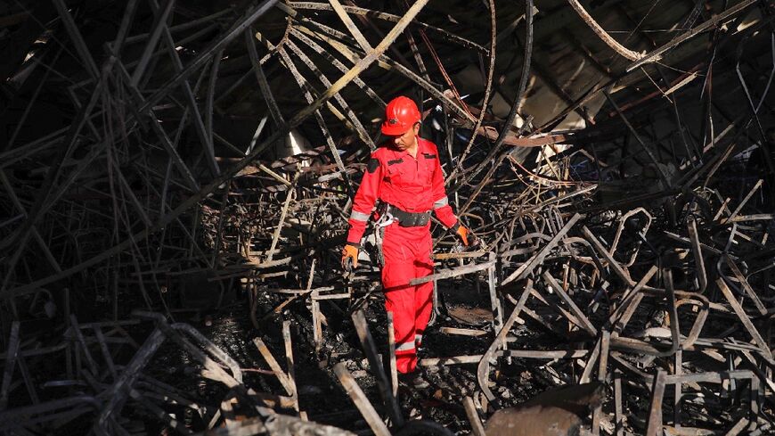 A firefighter surveys the charred and mangled interior of the reception hall where hundreds of Iraqis had been celebrating a wedding