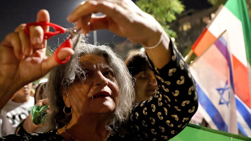A demonstrator cuts a lock of her hair during a gathering, by Israelis of Iranian origin, in support of Iran protests in the Israeli coastal city of Tel Aviv on Oct. 29, 2022.