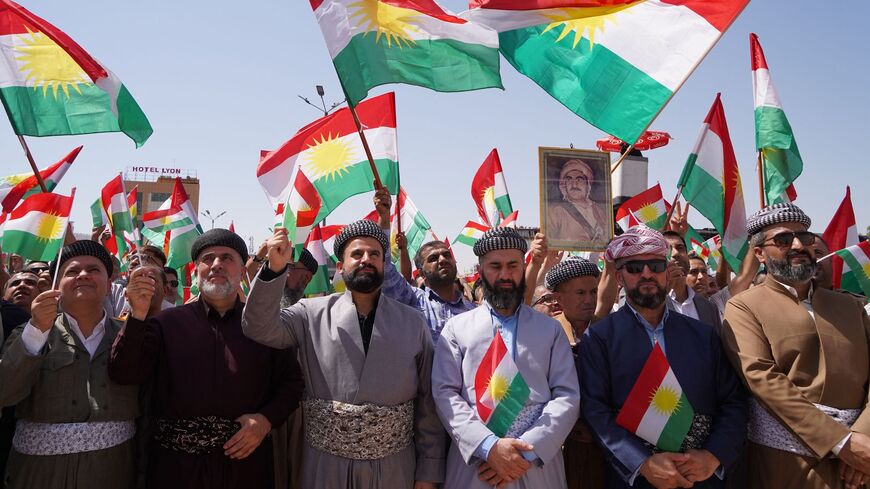 People lift the regional flag during a rally in Dohuk city.