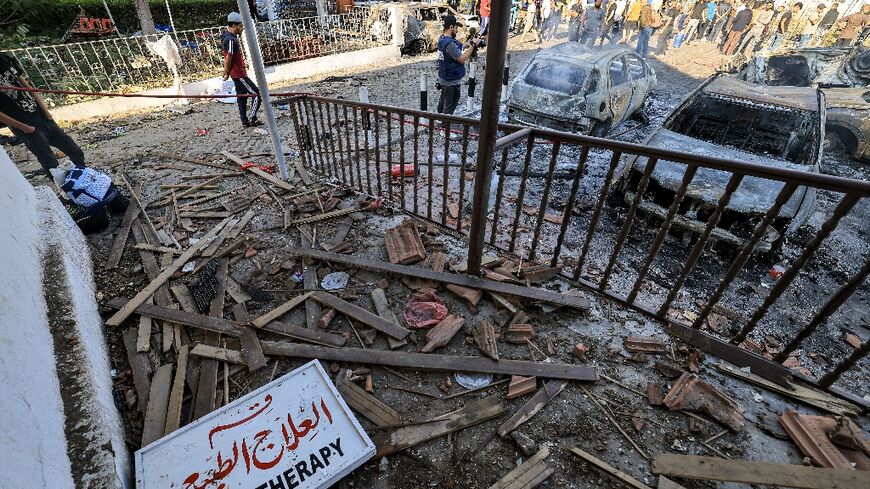 People search through debris outside the site of the Ahli Arab hospital in Gaza City on October 18, 2023 in the aftermath of an overnight strike there. 