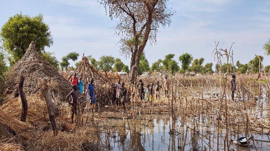 Children stand among the rooftops of homes destroyed by floodwaters in Yusuf Batir refugee camp in Maban, South Sudan, on November 25, 2019 -- UNICEF says tens of millions of children were displaced by climate disasters from 2016 to 2021