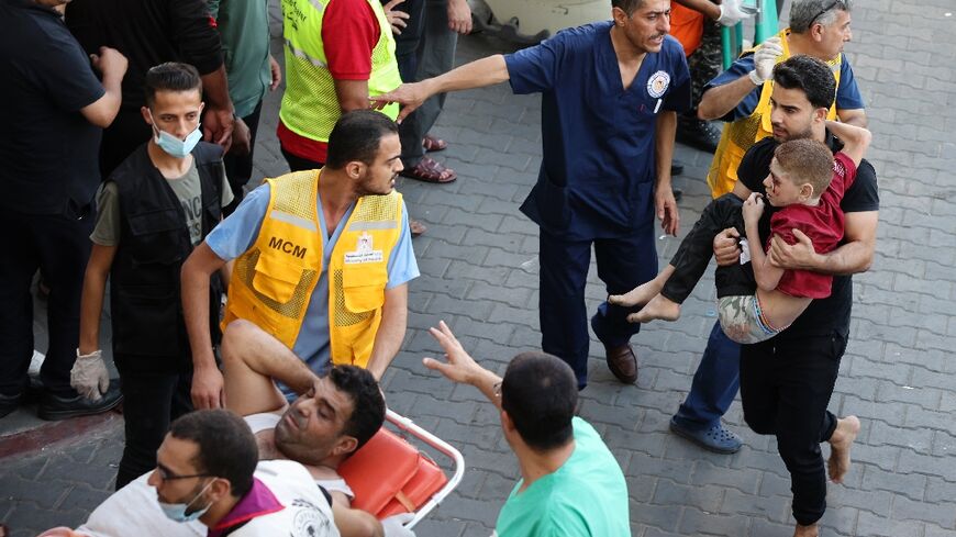 A man carries a wounded child into Gaza's Al-Shifa hospital following Israeli strikes on the coastal enclave on Tuesday