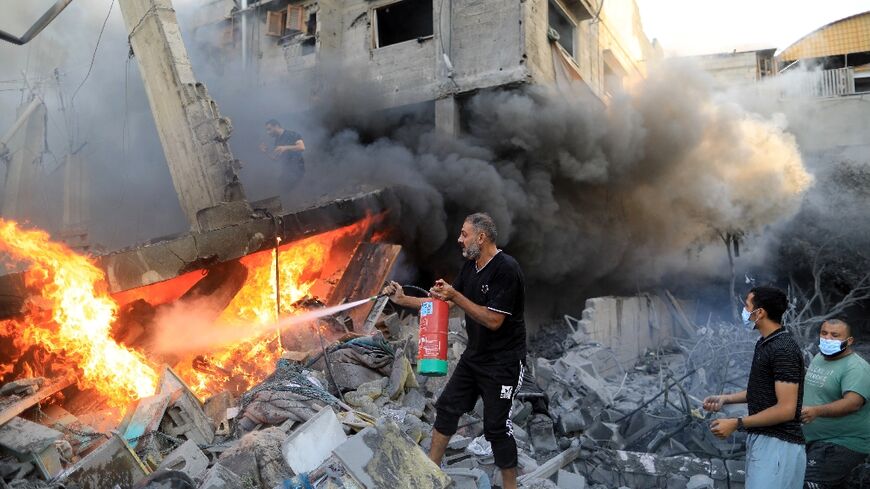 A Palestinian man uses a fire extinguisher to douse a fire following an Israeli strike in Khan Yunis in the southern Gaza Strip