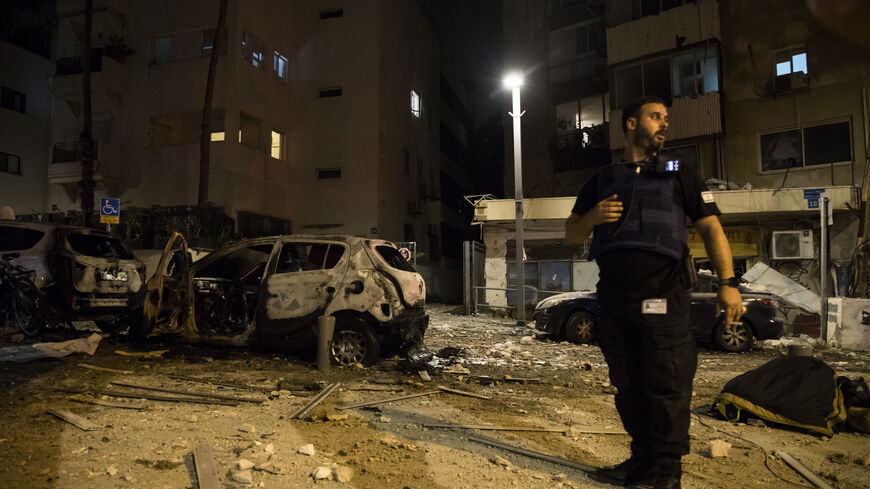 : Israeli security forces stand near a burned car at a scene where a rocket fired from Gaza strip hit a building on October 7, 2023 in Tel Aviv, Israel. Israel's Defense Forces (IDF) say that Hamas "had begun a massive shooting of rockets from the Gaza Strip into Israeli territory" which the Palestinian militant group has taken responsibility for. The IDF also say that militants had entered Israeli territory in "different locations". A counter attack has been launch against Gaza. (Photo by Amir Levy/Getty I