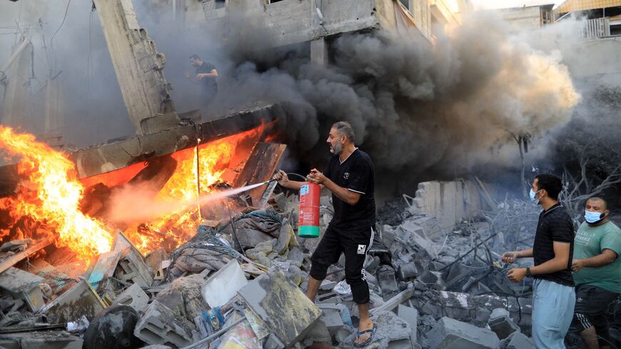 A Palestinian man uses a fire extinguisher to douse a fire following an Israeli strike, in Khan Yunis in the southern Gaza Strip on Oct. 14, 2023, as fighting between Israel and the Hamas movement continues for the eighth consecutive day.