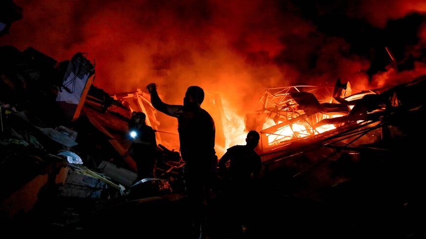 Smoke and fire rise from buildings as people gather amid the destruction in the aftermath of an Israeli strike on Gaza City on Oct. 26, 2023, as battles continue between Israel and the Palestinian Hamas group. 