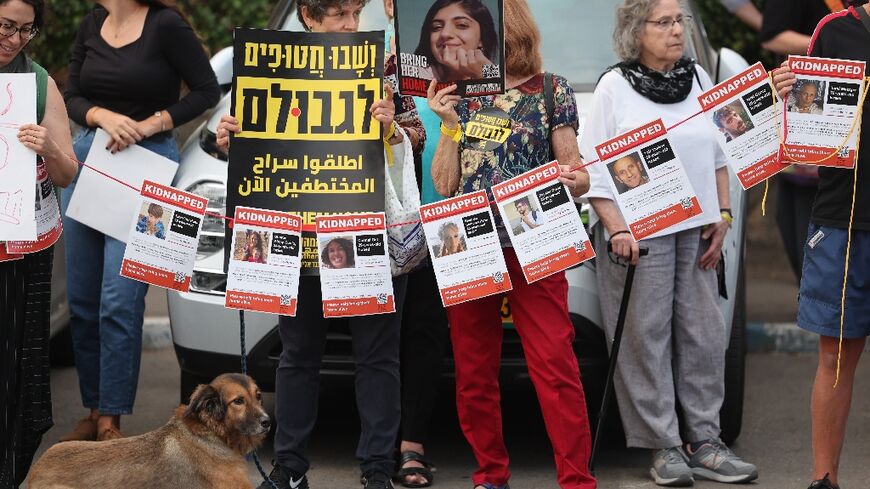 Demonstrators carry posters with the images of hostages held in Gaza outside the Israeli president's residence in Jerusalem