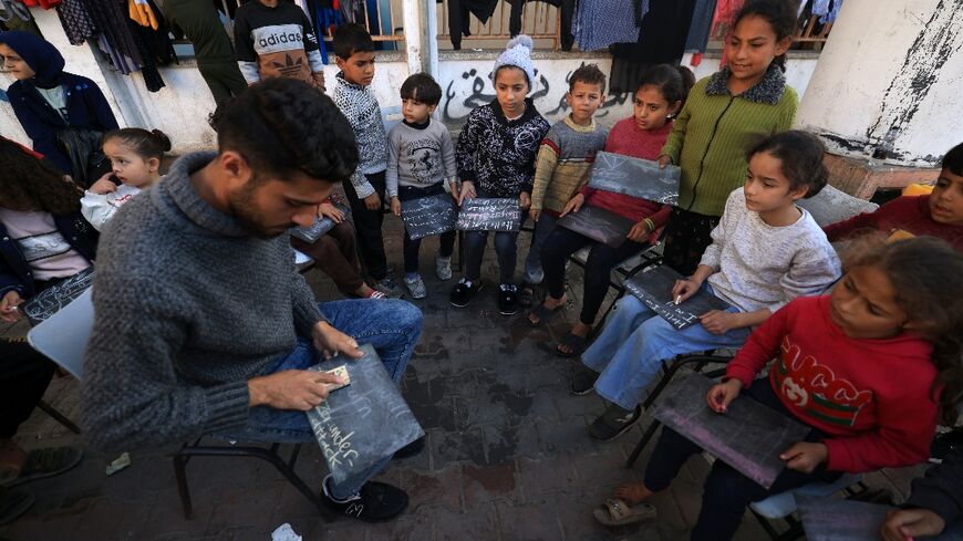 Tareq al-Ennabi, a 25-year-old English teacher, gathers displaced children at the Taha Hussein school in southern Gaza