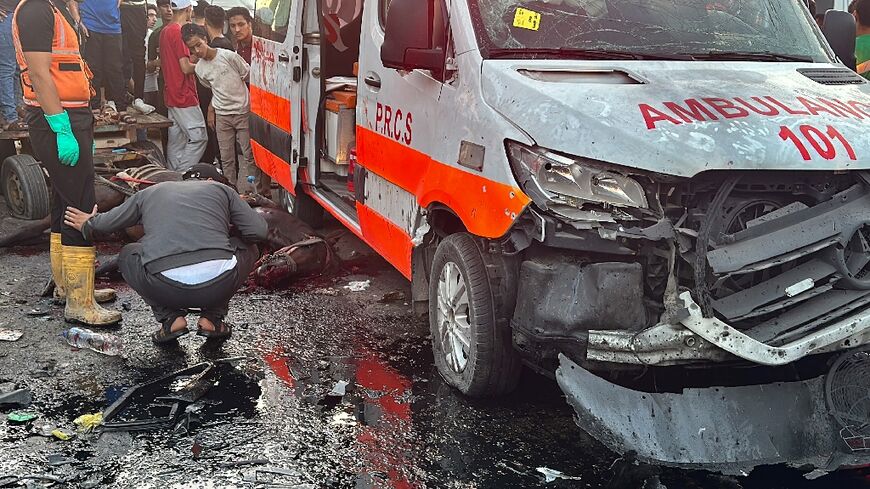 Onlookers outside Gaza's largest hospital Al-Shifa gather around a Red Crescent ambulance damaged in a deadly Israeli strike