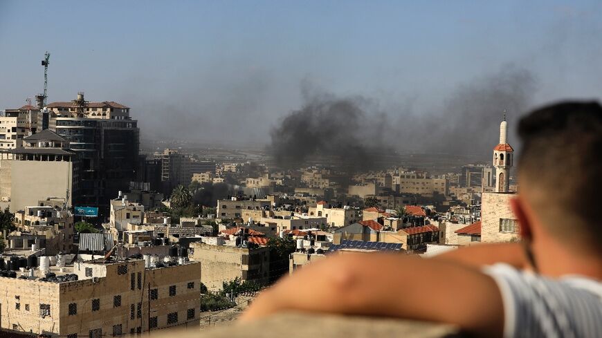 A child watches smoke rising from the Jenin Palestinian refugee camp, during clashes after an Israeli raid