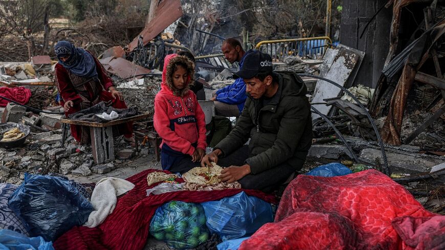 Palestinians eat outside amid the destruction caused by Israeli strikes in the Gaza Strip