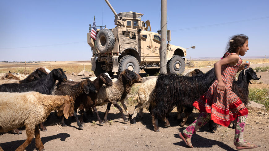 A girl runs past a U.S. Army Oshkosh M-ATV Mine Resistant Ambush Protected (MRAP) vehicle on May 26, 2021 near the Turkish border in northeastern Syria. 